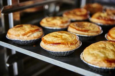 Meat pie with golden crust, visible filling, and a fork.