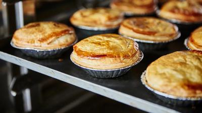 Meat pie with golden crust, visible filling, and a fork.