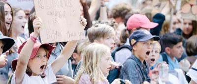 Protest sign held high, crowd visible, Winchester Cathedral in background.