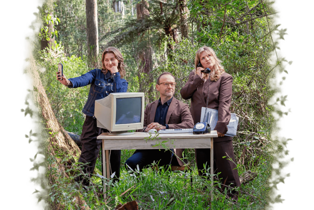 The habitat podcast hosts in a forest clearing with a desk, an old computer monitor and a rotary phone.
