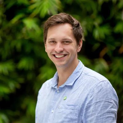 Man in suit, holding a microphone, speaking at a podium.