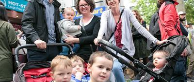 Woman in white coat, holding a clipboard, smiling, looking at camera.