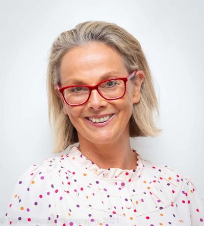 Woman, Liv Casben, smiling, outdoors, wearing a hat, trees in background.