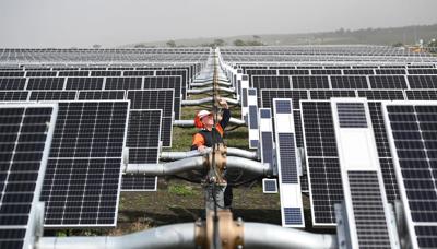 Solar farm landscape, panels arrayed, blue sky.
