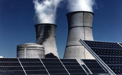 Solar panel array with nuclear power plant in background.