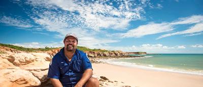 Ranger in uniform, standing in a forest, looking at the camera.