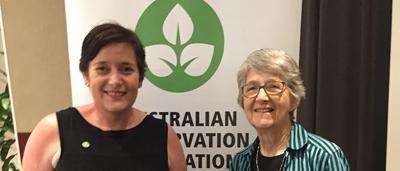 Woman in field, holding flowers, smiling.