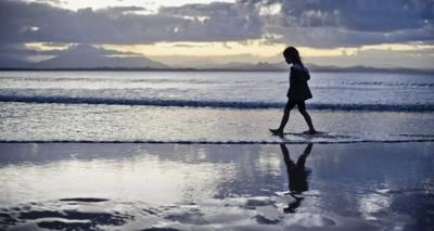 Child walking, holding hands, with adult, green landscape, trees.