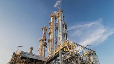Gas plant with smokestacks against a blue sky.