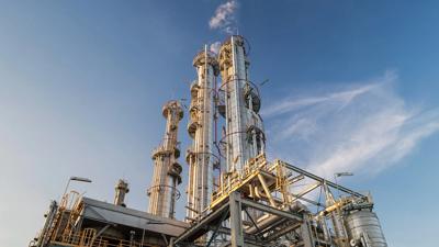 Gas plant with smokestacks against a blue sky.