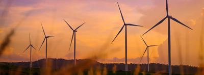 Sunset over ocean, wind turbines, twilight sky.
