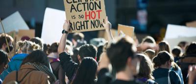 Woman in a white coat, holding a plant, in a lab setting.