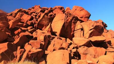 Rock art panel, red ochre figures, Murujuga, Western Australia.
