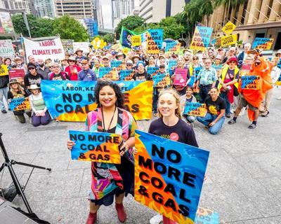 Brisbane skyline at dusk, with city lights reflecting on the river. "Rise Up" text overlay.