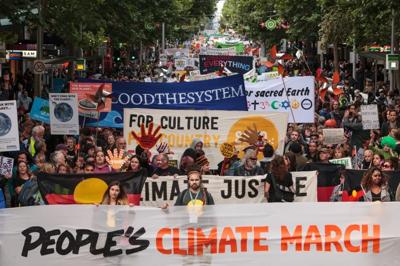 Climate march graphic: Crowd with signs, buildings, and a green tree.