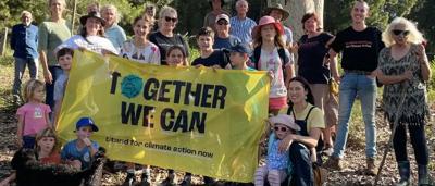 Woman speaking at a podium, Eden-Monaro sign, Australian flag, outdoor setting.