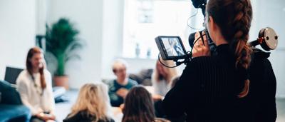 A brown bear standing on hind legs in a forest, sunlight filtering through trees.