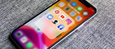 Person in a white shirt, standing in front of a building with a glass facade, sunny day.