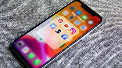Person in a white shirt, standing in front of a building with a glass facade, sunny day.