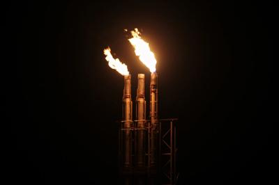 Gas flares burning at night, industrial landscape.