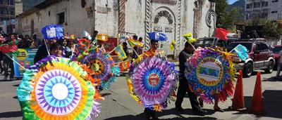 Woman in a white coat, holding a clipboard, smiling, looking at a computer screen.