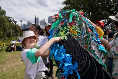 March for Nature 2024: Crowd of people marching with signs, trees in background, sunny day.