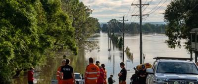Sydney flooded street, cars submerged, buildings in background, overcast sky.