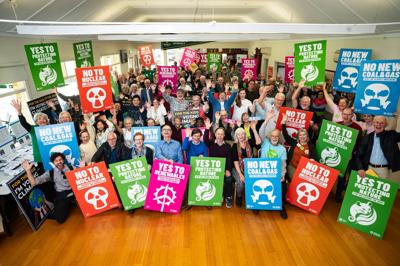Woman in a field, holding a camera, looking at a mountain range.